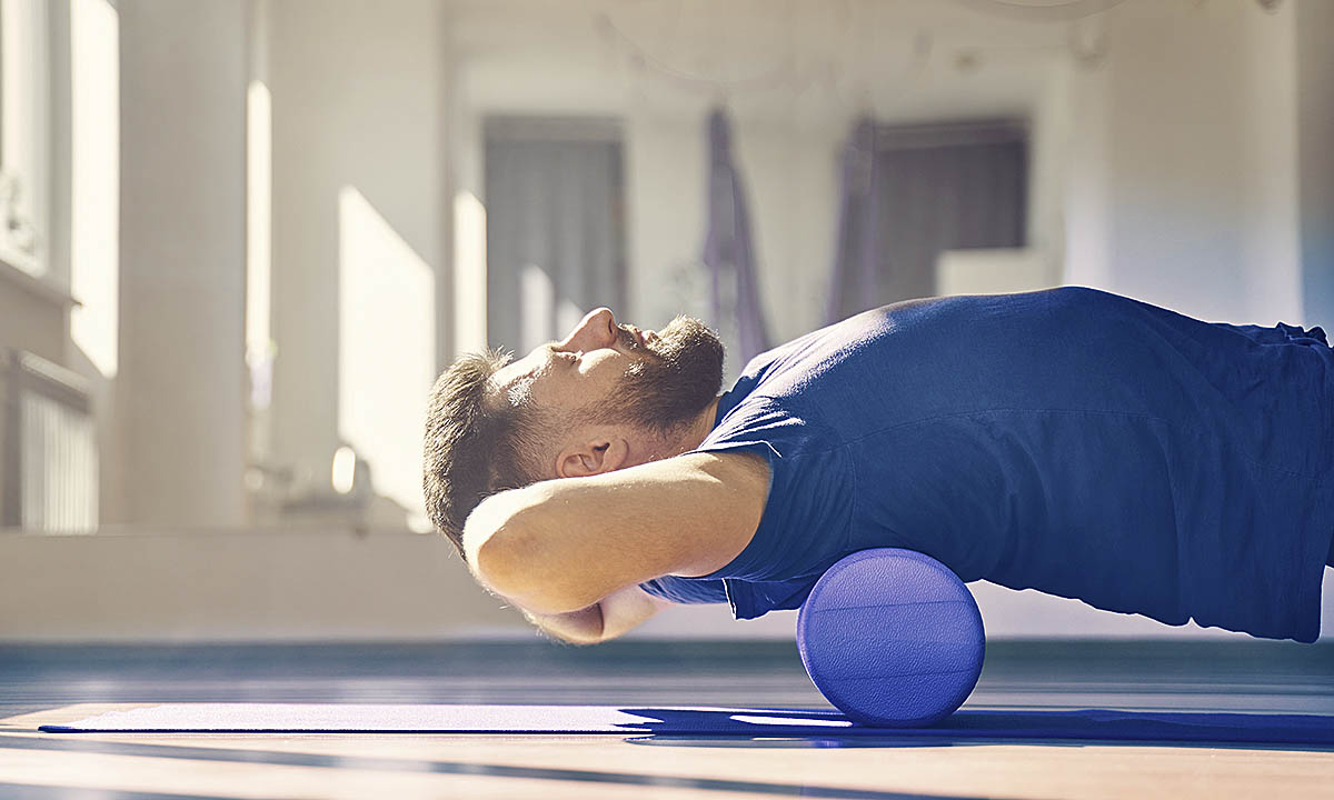 Mann beim Training auf Faszienrolle